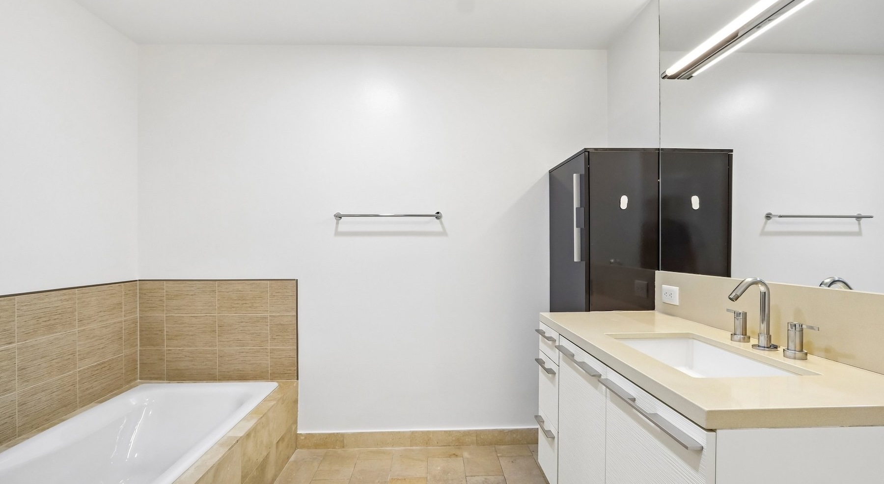 a bathroom with a tub, sink and mirror